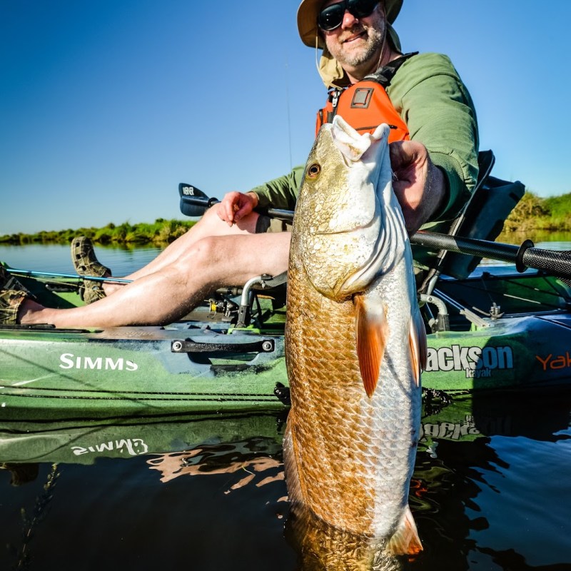 A man showing off a large redfish out of a kayak